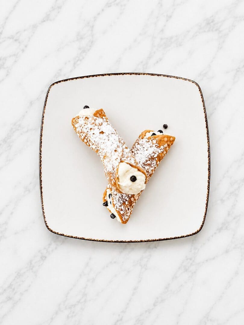 Two powdered cannoli with chocolate chips